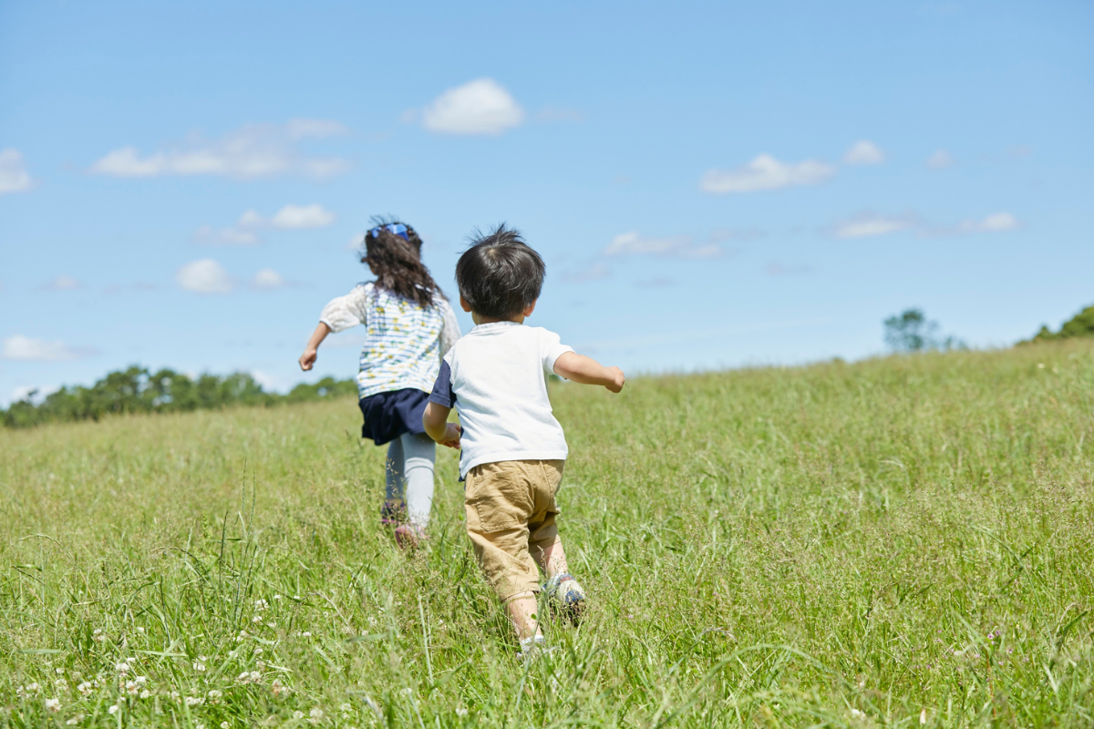 kids running is green grass field with bright blue skies